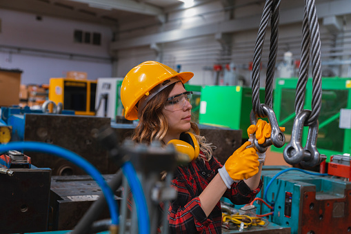 Young engineer woman holding and working with cable winch for operating crane