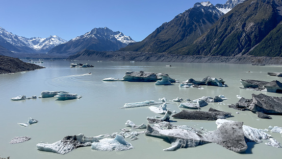 Icebergs floating on the milky surface of the water in the alpine Tasman Glacial lake in the Aoraki Mt Cook National Park