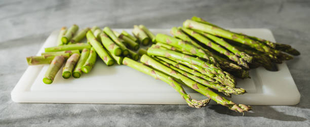 istock Fresh raw green asparagus close-up on a white cutting board on a grey background 1475205987