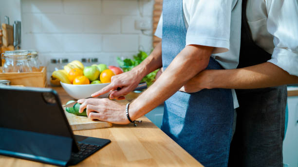 istock Young Man Hugging Boyfriend from Behind When He's Cutting Vegetables. 1475211690