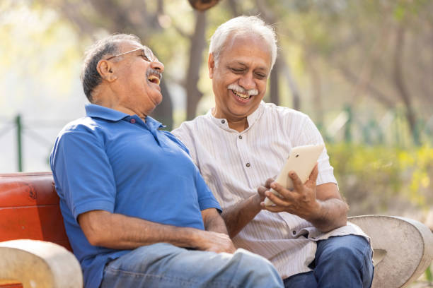 istock Two senior male friends using digital tablet at park. 1475212182