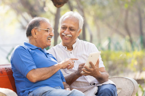 istock Two senior male friends using digital tablet at park. 1475212194