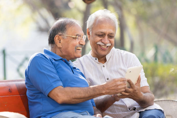 istock Two senior male friends using digital tablet at park. 1475212195