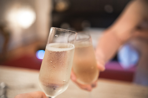 Man cheering with a glass of champagne with his partner who are celebrating an event