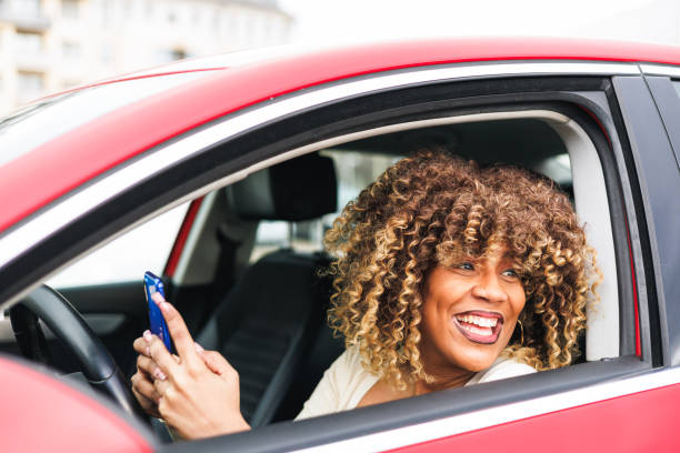 istock afro woman in red car using blue phone and laughing 1475216431