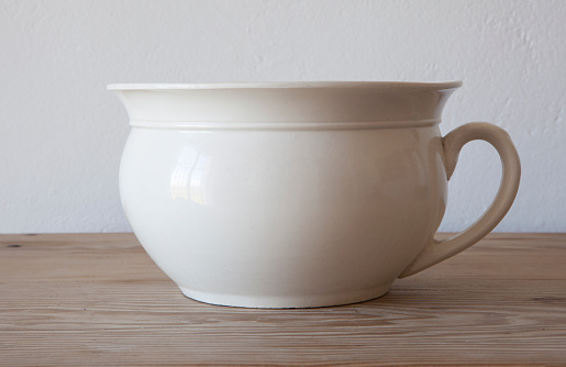 White porcelain camber pot over wooden surface. Selective focus
