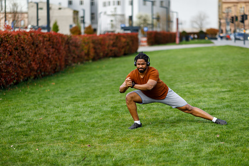 A Handsome African Man is Enjoying an Exercise while Stretching Legs in a Grass Field.