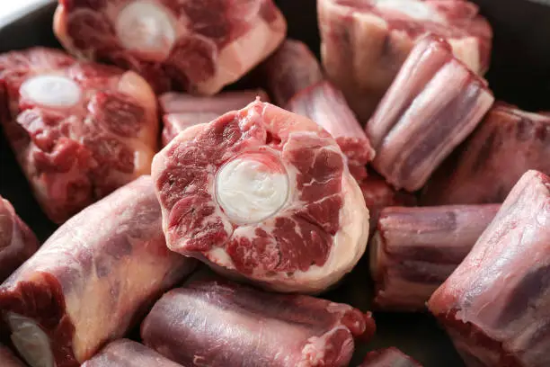 Raw pieces of oxtail with bone, gelatin-rich meat, usually slow-cooked as a stew or braised, traditional stock base for oxtail soup, selected focus, narrow depth of field
