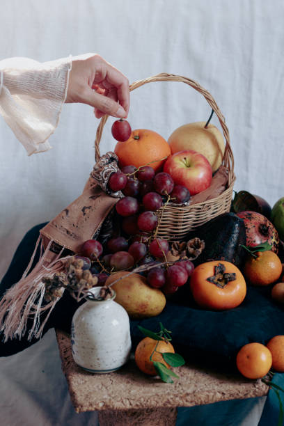 istock Vertical shot of dainty hand holding a grape over a table filled with twelve different round fruits 1475220921