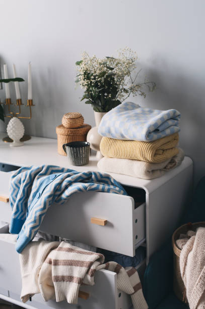 white scandi drawer with messy knitted sweaters. Spring home cleaning and wardrobe organization. Sorting clothes.