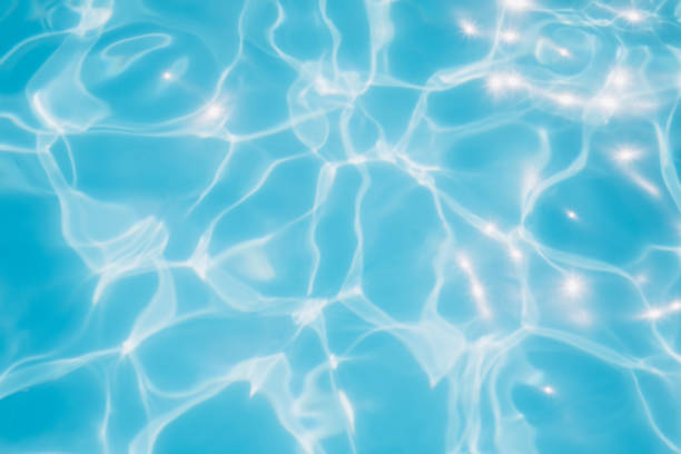 Background, blue water waves in the pool with sun reflection. Selective focus stock photo