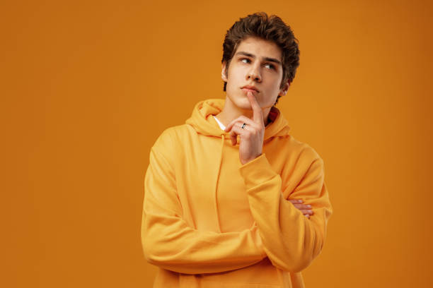istock Young man thinking about things on yellow background 1475225224