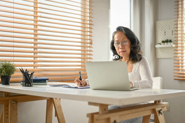 istock A focused 60-year-old Asian businesswoman working from home, using laptop 1475228078