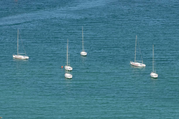 Doha, Qatar - March 19, 2023: Aerial view of a white yacht with a sail. Ship in the blue sea Corniche beach Doha