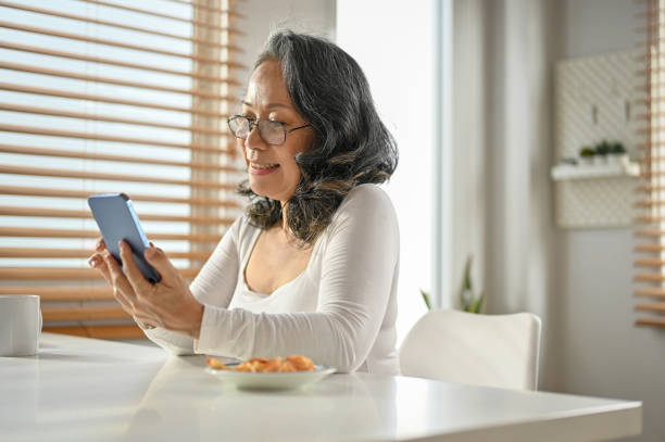 istock A happy Asian-aged woman using her smartphone, chatting with someone 1475228288