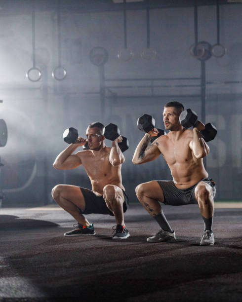 мускулистый рост спортсменов мужского пола тренируется с гантелями в тренажерном зале. - gym muscular build weights two people стоковые фото и изображения
