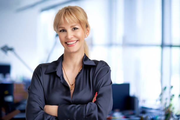 Confident businesswoman standing at the office with folded arms stock photo