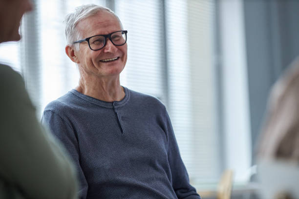 Smiling senior man laughing while chatting with friends in retirement home