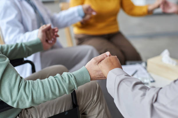 istock Close up of elderly people holding hands in circle during support group session 1475231220