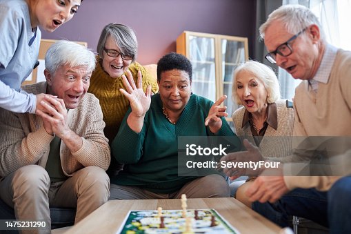istock Senior people playing board games at retirement home with surprised emotion 1475231290