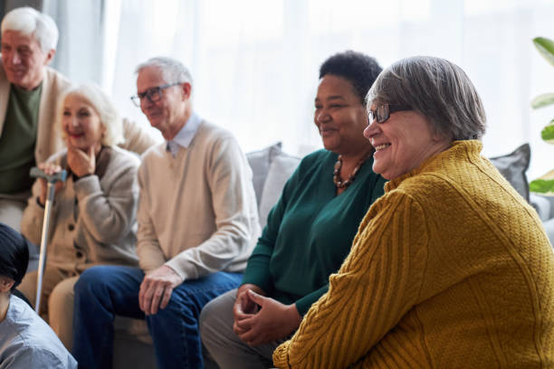 Senior people watching TV while sitting in row in retirement home facility