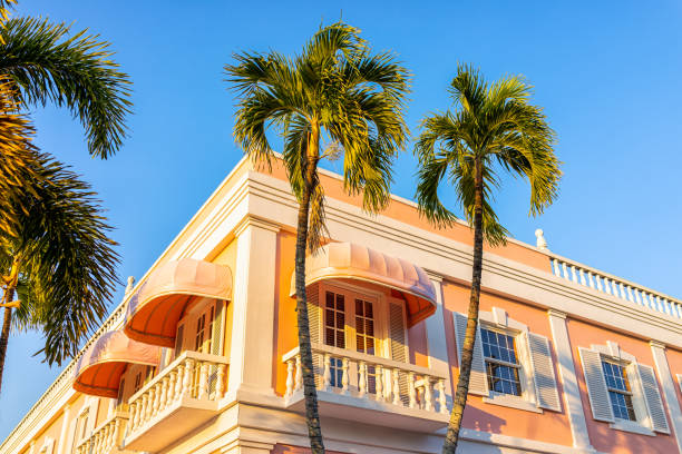 old town naples, florida centro de la ciudad en el distrito comercial third street south con arquitectura de edificio rosa exterior al atardecer con palmeras y cielo azul bebé - florida naples florida house residential structure fotografías e imágenes de stock