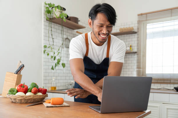 istock Man in kitchen looking at recipes on laptop while cooking 1475233144