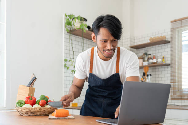 istock Man in kitchen looking at recipes on laptop while cooking 1475233154