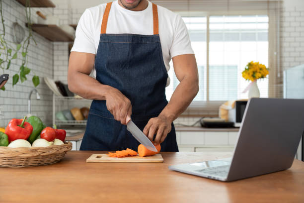 istock Man in kitchen looking at recipes on laptop while cooking 1475233183