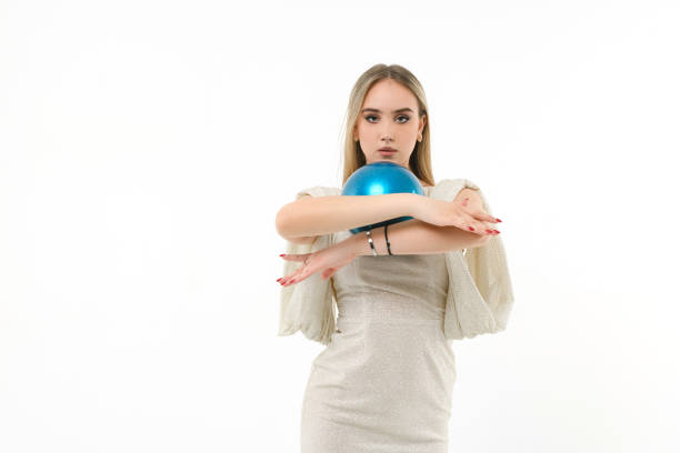 Candid shot of cool young blond woman dancing against powder blue background. She is smiling at camera with confidence.