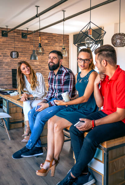 equipo de oficinistas hablando sentado sobre la mesa en coworking - break office 30s 20s fotografías e imágenes de stock