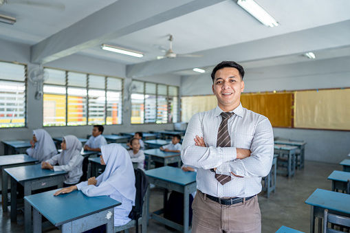 Confident school teacher standing in the classroom