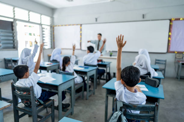 Students raising their arms during teacher's lesson at elementary school