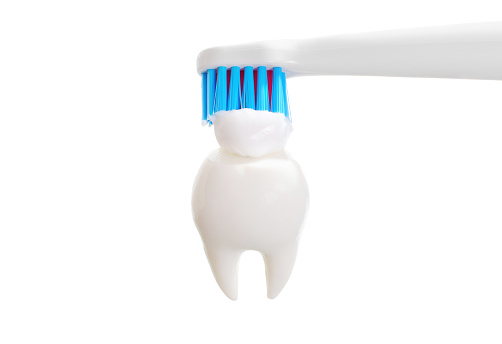 Close-up view of an electric toothbrush applying toothpaste to a tooth model. Regular dental care and oral hygiene concept.