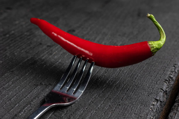 istock A red chili pepper on a fork on a black table. 1475236662