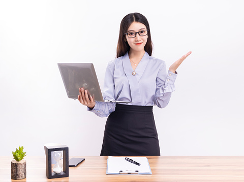 A business woman in a blue suit standing at her desk