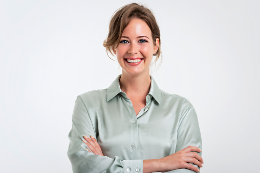 Studio portrait of attractive business woman standing with arms crossed at isolated white background. Copy space.