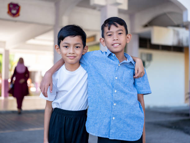 Elementary school friends embracing each other and looking at camera