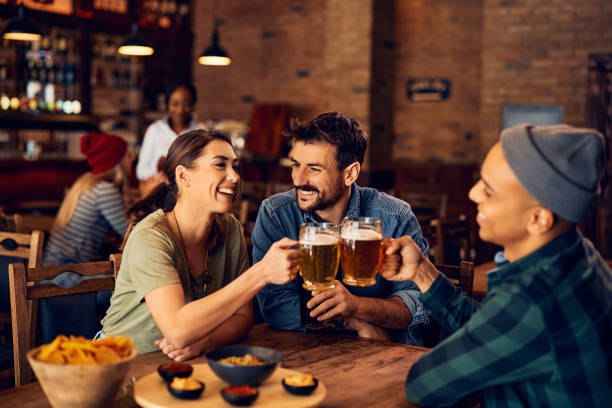 istock Young cheerful people toasting with beer while gathering in a pub. 1475239901