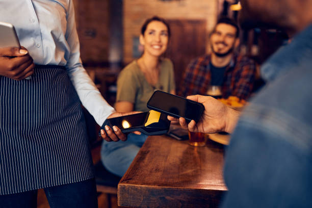 istock Close up of man paying with mobile phone in a pub. 1475240005