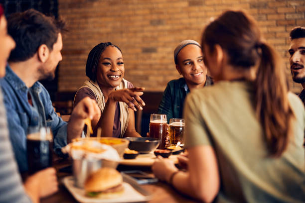 istock Happy black woman talking to her friends while drinking beer in pub. 1475240762