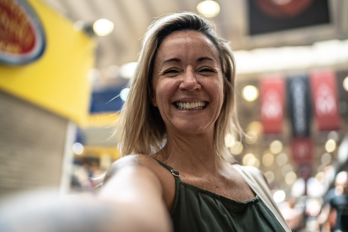 Mature woman taking selfies or filming in a market hall - point of view
