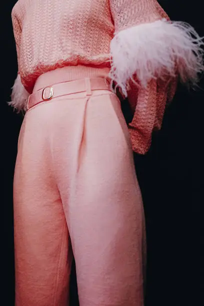 Fashion female figure in stylish knitting pink set sweater and pants on black background. Fashion details