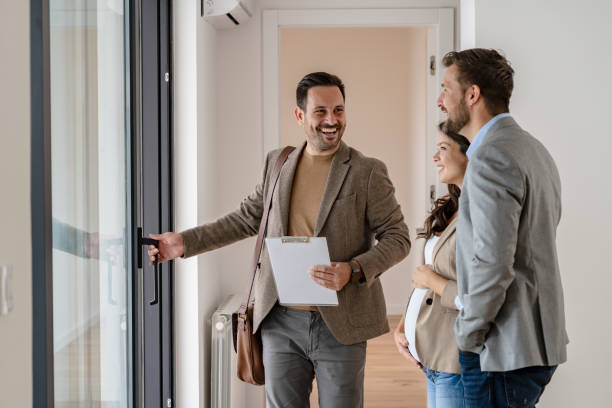 joven pareja casada hablando con un agente de bienes raíces que visita un apartamento en venta o en alquiler - inmobiliaria fotografías e imágenes de stock