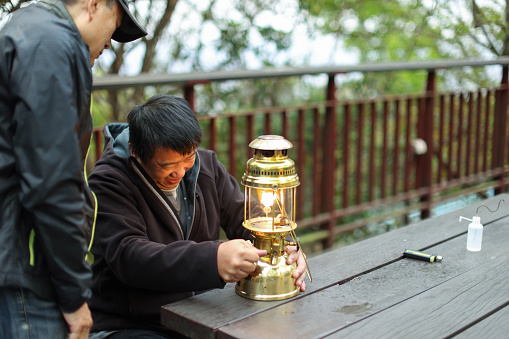 Man camping outdoors is instructing how to use gas lamps