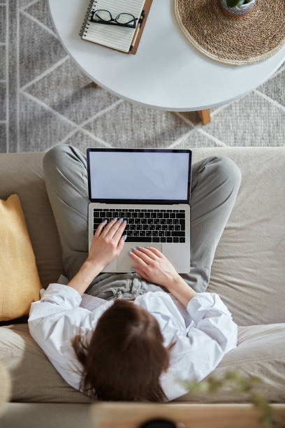 istock Mockup white screen laptop woman using computer sitting on sofa at home, top view 1475252942