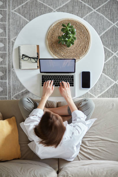 istock Mockup white screen laptop woman using computer sitting on sofa at home, top view 1475253451