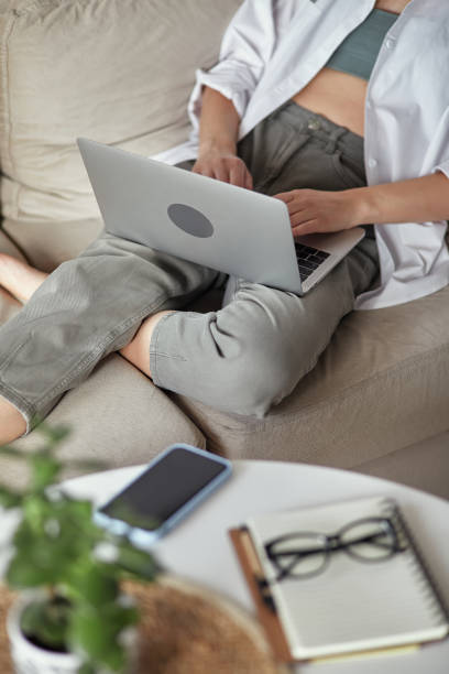 istock Close up woman hand using laptop sitting on sofa at home, remote work at home 1475254866