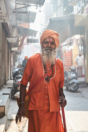 Amritsar, Punjab, India - Sadhu in traditional orange clothing walking down a road in early morning