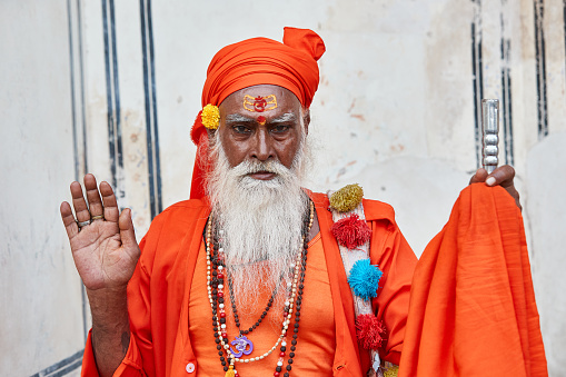 Jaipur, Rajasthan, India - Holy man in guru outfit posing for tourists for money